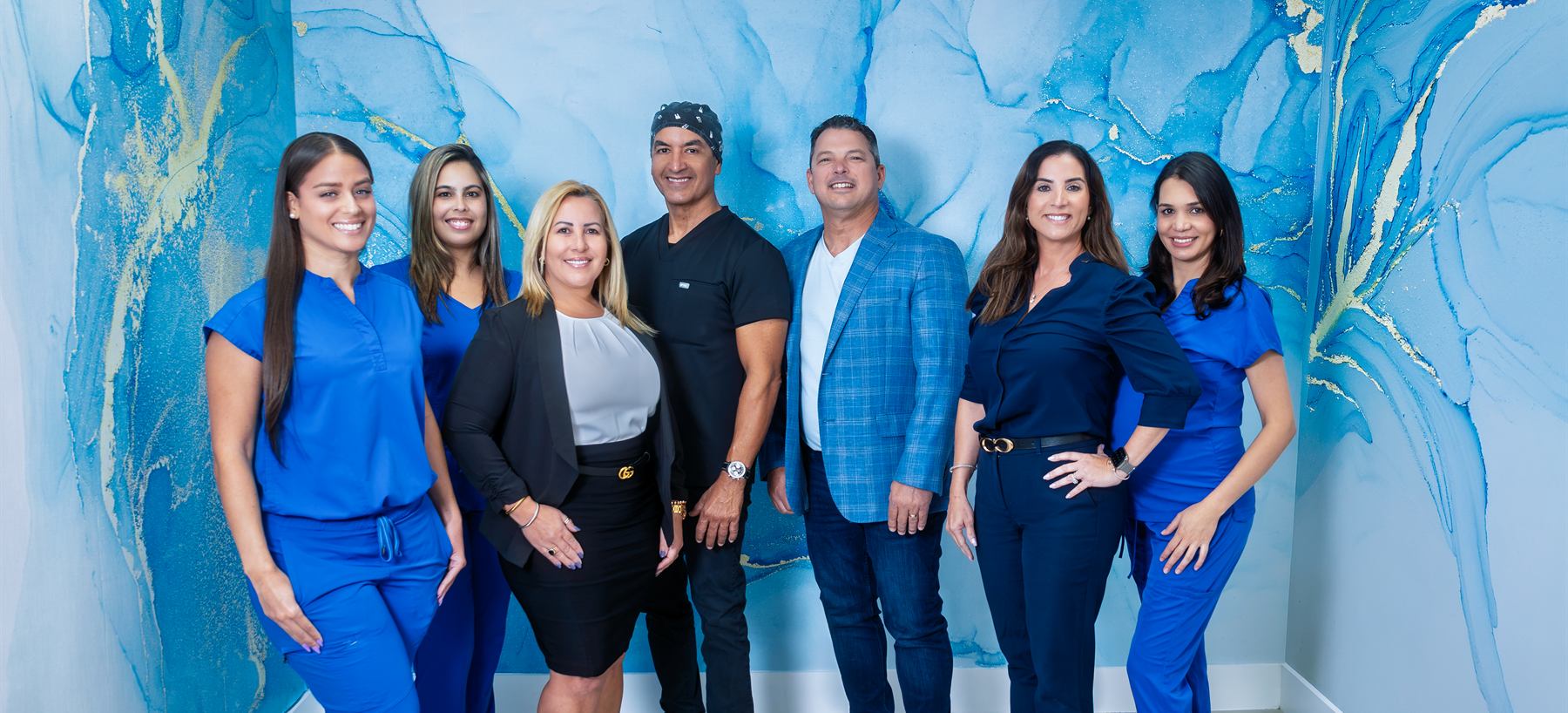 El equipo de Estelar Dental, siete personas de pie ante la pared azul de la clínica.